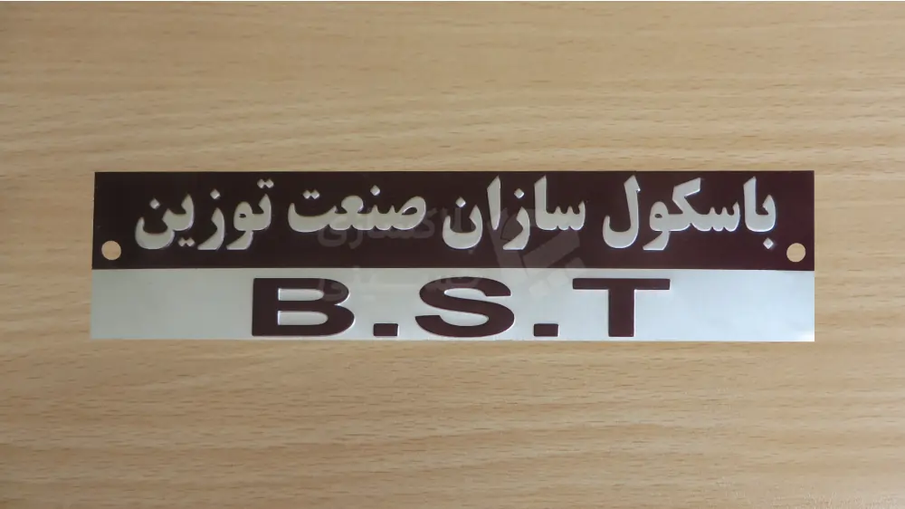 چاپ پلاک برای باسکولسازان صنعت توزین با آرم B.S.T پلاک ترازو و باسکول با متن فارسی «باسکولسازان صنعت توزین» و مخفف B.S.T