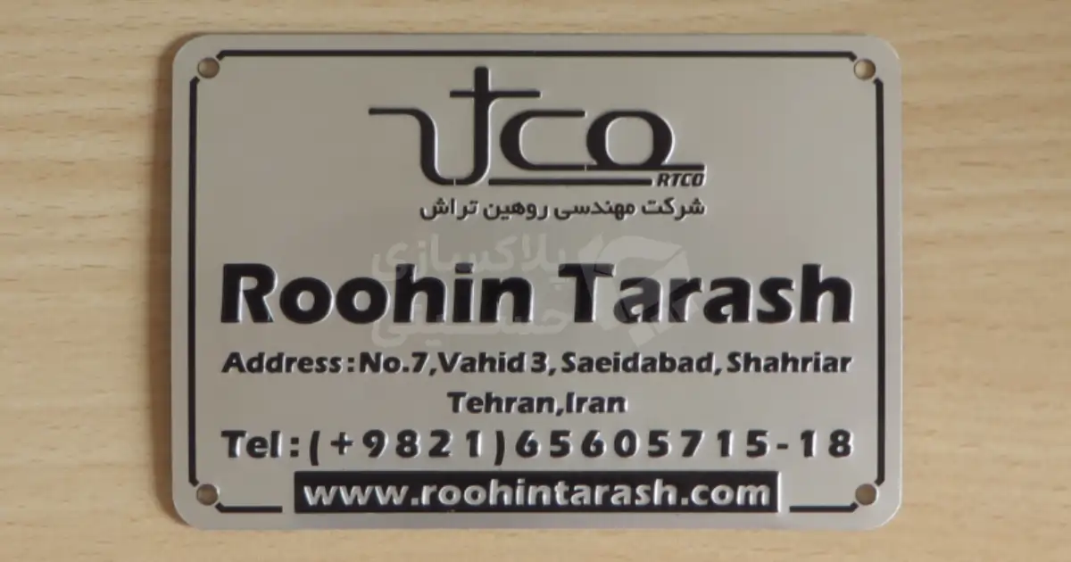 پلاک دستگاه صنعتی شرکت مهندسی روهین تراش (Roohin Tarash) با لوگو و اطلاعات تماس روی زمینه چوبی